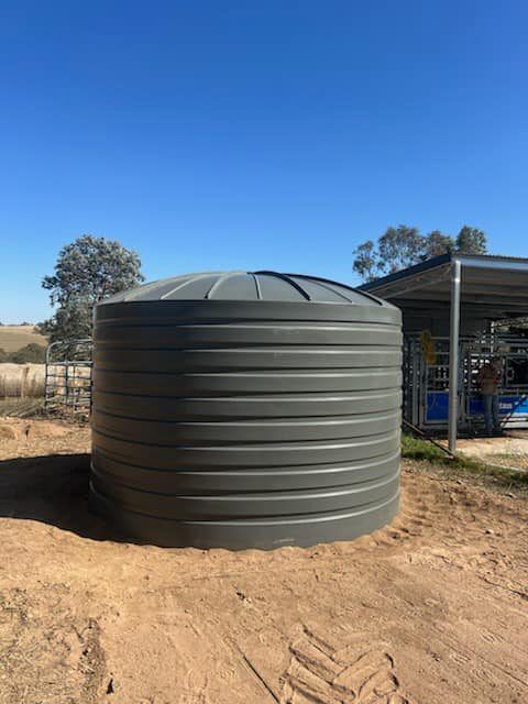 Round poly rainwater tank installed on a prepared pad on a rural block