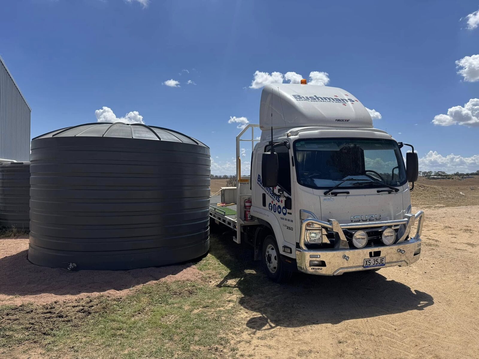 Large corrugated rural water tank delivered and positioned beside the delivery truck