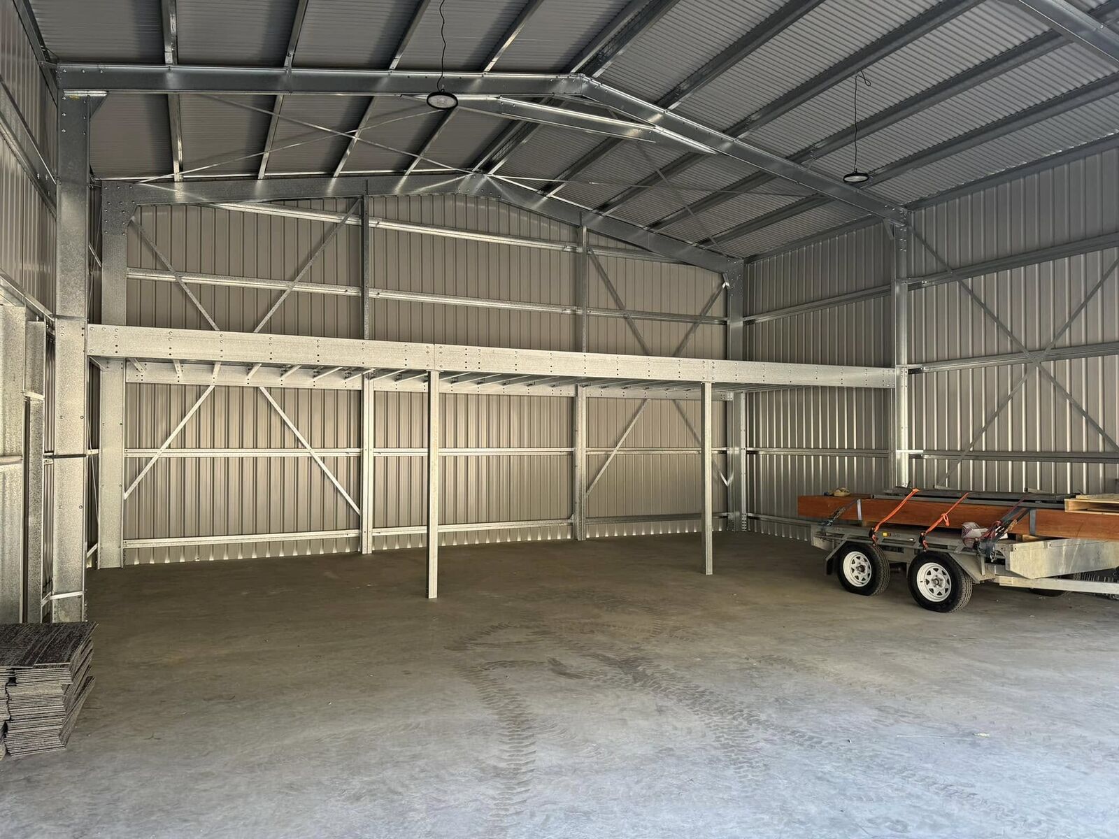Interior of an open-bay machinery shed with steel framing and a concrete floor