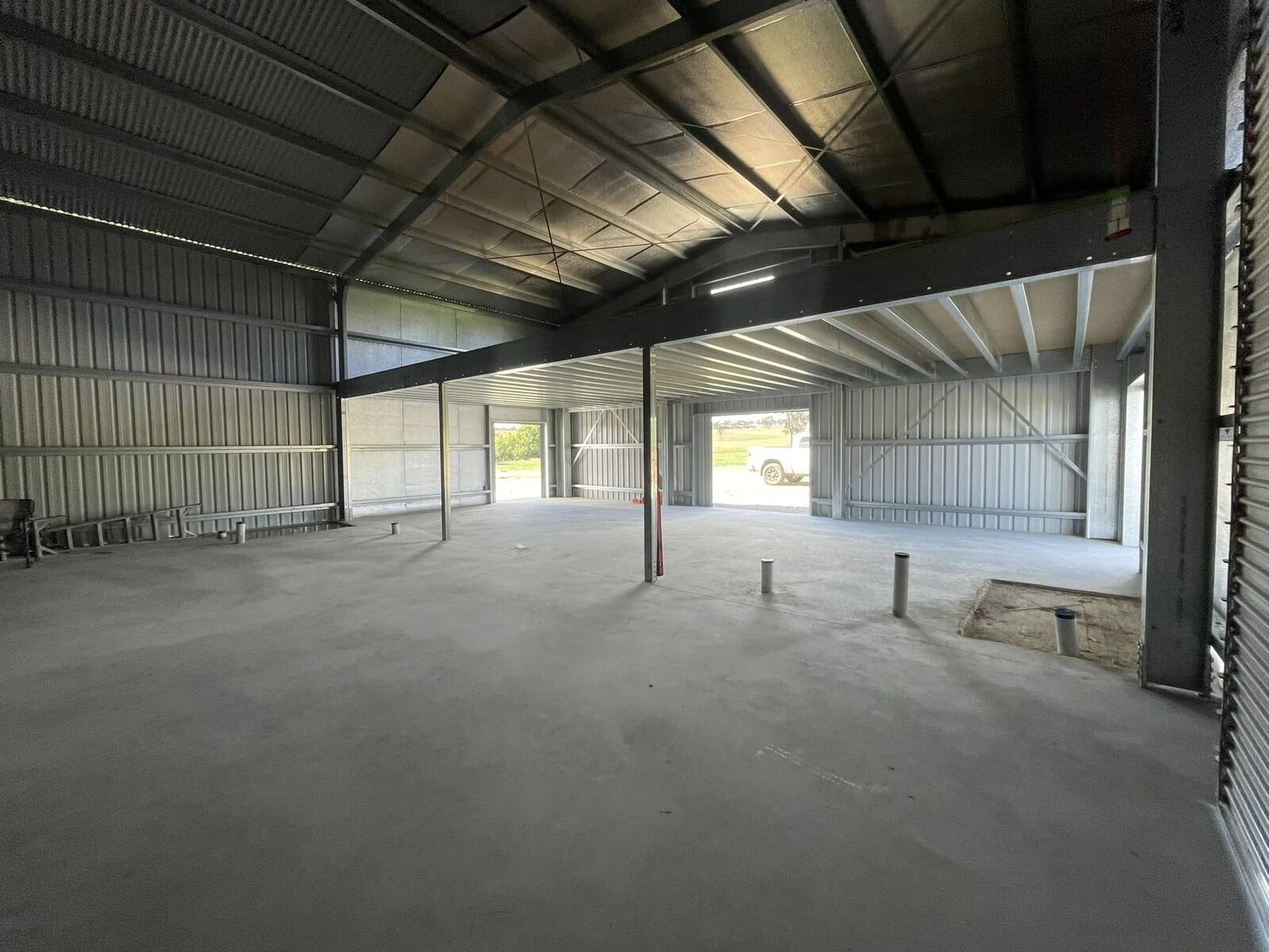 Inside a large clear-span steel shed with roller doors and a polished concrete floor