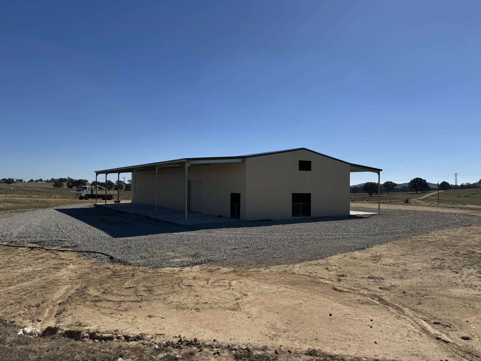 Two-tone cream and grey Colorbond shed with an attached awning on a rural property