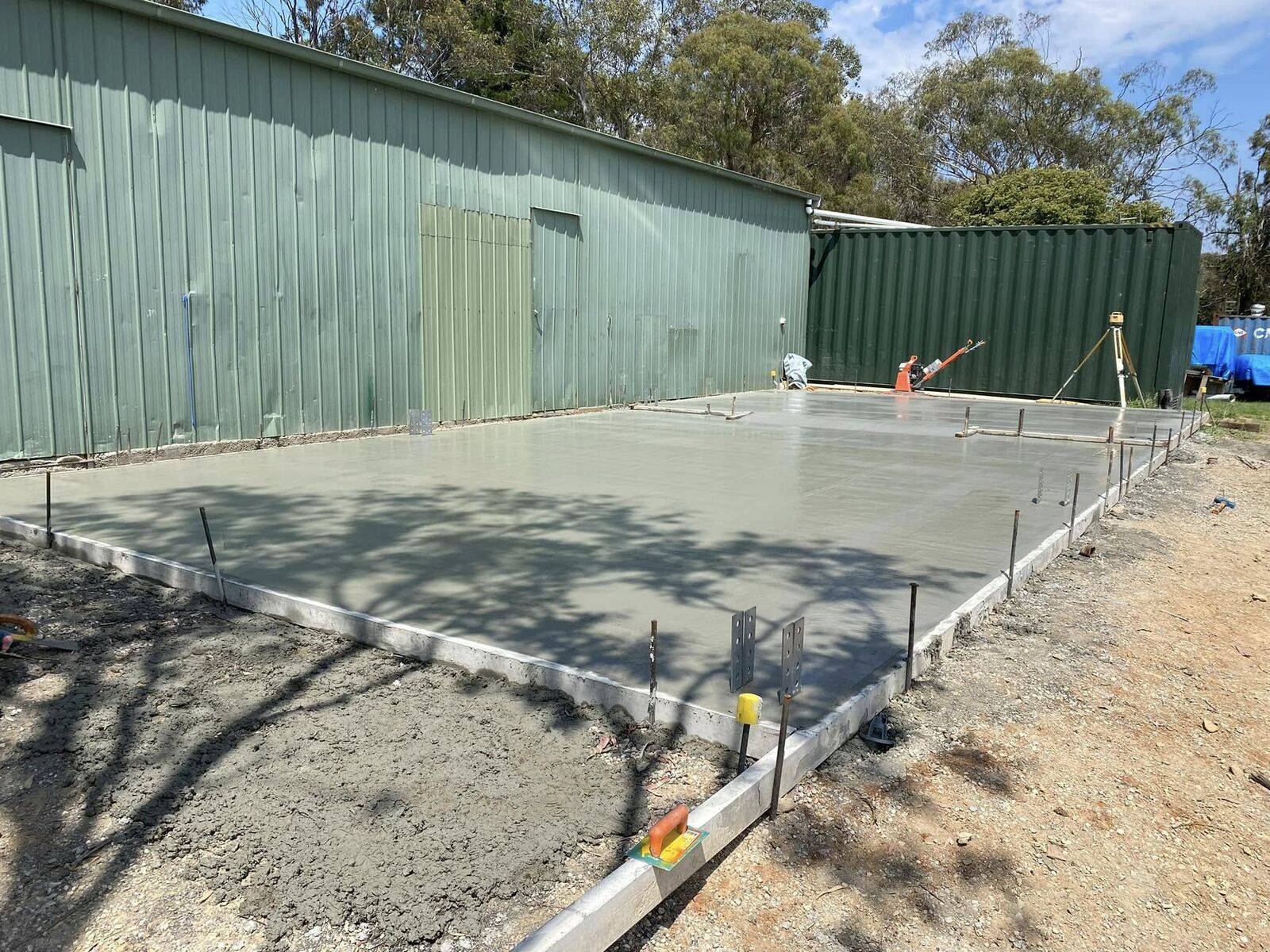 Green Colorbond farm shed with a freshly poured concrete slab during construction