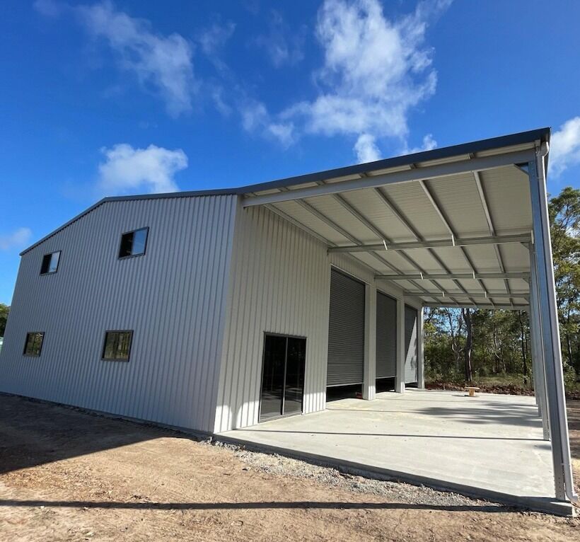 Large two-storey American barn-style steel shed with an open carport awning