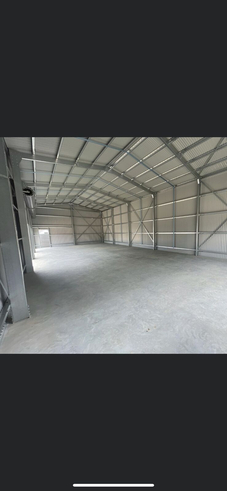 Inside a completed steel workshop with a smooth concrete floor and roller-door access